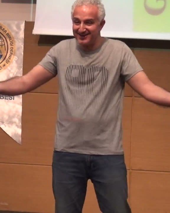 Zafer Yılmaz bir seminerde kollarını açmış, dinleyicilere konuşurken